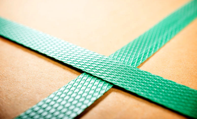 Groene plastic omsnoeringsband rond een kartonnen doos
