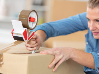 Vrouw brengt tape aan op kartonnen doos met tapedispenser