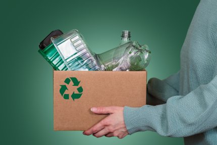 Vrouw draagt doos met gerecyclede plastic flessen